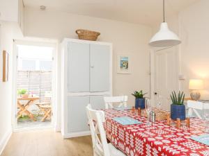 a white dining room with a table and chairs at Windygates in Rhosneigr