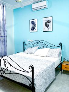 um quarto com uma cama com uma parede azul em Villa Soudan em Bobo-Dioulasso