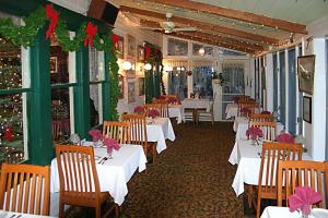 un restaurante con mesas y sillas blancas y adornos navideños en Inn at Starlight Lake & Restaurant, en Starlight