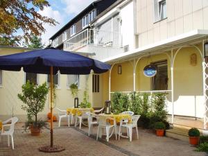 a patio with tables and chairs and an umbrella at Hotel-Restaurant Kranefoer in Waltrop