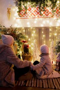 two children sitting on a rug in a room with christmas lights at Raxti in Kuldīga