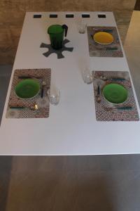 a white table with two green plates and glasses on it at Casa Coltura in Bormio