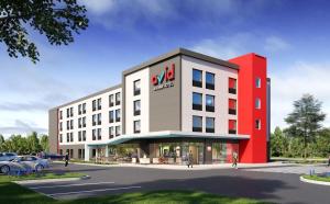 avid hotels - Round Rock South, an IHG Hotel في راوند روك: تقديم عماره فندقيه بسيارات متوقفه في موقف