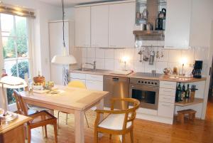 a kitchen with white cabinets and a wooden table at Haus Rothenstein, ruhige FeWo, ca. 10 min. zu Messe und Flughafen in Meerbusch