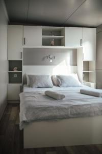 - une chambre avec un grand lit blanc et des armoires blanches dans l'établissement Rasin Mobile Homes, à Pakoštane