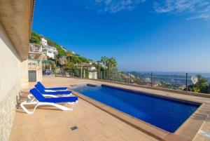 een zwembad met 2 ligstoelen naast een huis bij Villa Breeze in Lloret de Mar