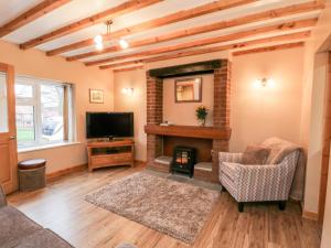 a living room with a fireplace and a tv at Barnaby Cottage in Yarm