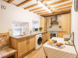 a kitchen with wooden cabinets and a sink and a dishwasher at Barnaby Cottage in Yarm