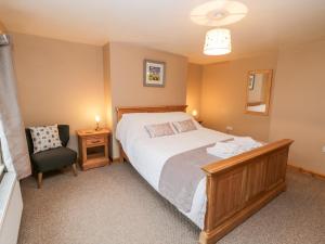 a bedroom with a large bed and a chair at Barnaby Cottage in Yarm