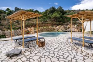 a patio with two umbrellas and a swimming pool at Casa Stones B&B in Cugnana