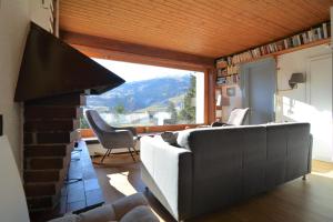 uma sala de estar com um sofá e uma grande janela em Haus Schwarz em Savognin