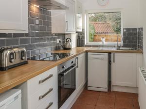 a kitchen with white cabinets and a sink and a window at Brinkburn Cottage in Scarborough