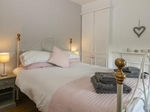 a bedroom with a white bed with pink pillows at Brinkburn Cottage in Scarborough