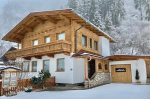 a house with a wooden roof in the snow at Ferienhaus Zimmereben in Mayrhofen