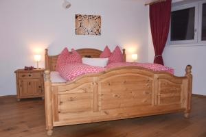 - une chambre avec un lit en bois et des oreillers roses dans l'établissement Ferienwohnung Heideggerhof, à Thaur