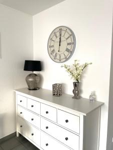 a white dresser with a clock on the wall at Innenstadt Neumarkt-Schildergasse stylische Wohnung in Cologne