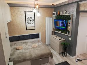a bedroom with a bed and a tv and a clock at Tomis Suite in Constanţa