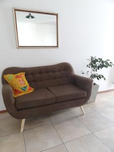a brown couch in a living room with a mirror at Dpto Paraná - Piscina, calefacción y aire acond in Córdoba