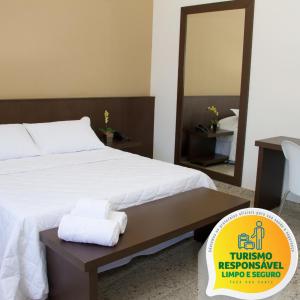Santorini Hotel في Guanhães: غرفة نوم مع سرير أبيض كبير مع مرآة