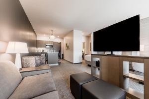 uma sala de estar com um sofá e uma televisão de ecrã plano em Hyatt House Winnipeg South Outlet Collection em Winnipeg