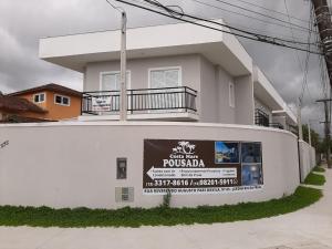 ein weißes Haus mit einem Schild davor in der Unterkunft Sobrado frente ao SESC, WIFI 300MB, 2 vagas auto, cozinha, churrasqueira, moderno e reformado in Bertioga