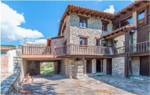 Cette grande maison en pierre possède un balcon. dans l'établissement Casa rural Molí del Salt - Cerdanya, à Viliella