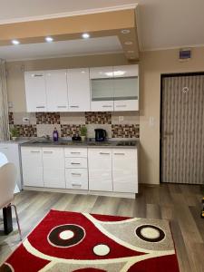 uma cozinha com armários brancos e um tapete vermelho em 8 RESIDENCE APARTAMENT em Cavnic