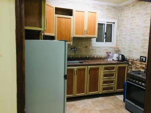 a kitchen with wooden cabinets and a refrigerator at Maadi Ring Road Sweet Apartment in Cairo