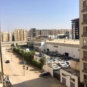 a parking lot with parked cars in a city at Maadi Ring Road Sweet Apartment in Cairo