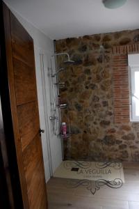 a bathroom with a stone wall and a door at CASA RURAL LA VEGUILLA in Fuente del Arco