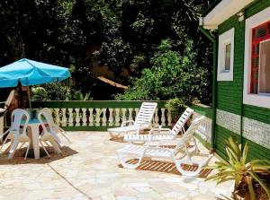 a group of chairs and an umbrella on a patio at Cobertura na Enseada a 80 m da areia in Ubatuba