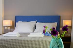 Una cama con cabecero azul y flores púrpuras en un jarrón en Elounda Colour Apartments, en Elounda