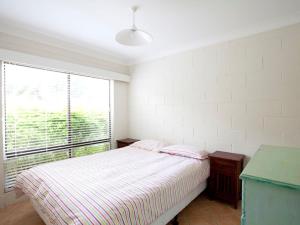 een slaapkamer met een bed en een groot raam bij Blueys Beach Villa Manyana 24 in Blueys Beach