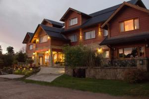 a large wooden house with lights in the yard at Alma Andina Hosteria in Villa La Angostura