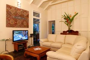 a living room with a couch and a tv at Port Douglas Cottage & Lodge in Port Douglas