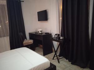 a bedroom with a bed and a desk and a television at ILITHA PARK in Cape Town