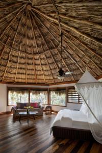 ein Schlafzimmer mit einem Bett und einem Strohdach in der Unterkunft Gaia Riverlodge in San Ignacio