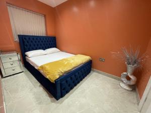 a bedroom with a bed with an orange wall at Modern Garden House in Harrow