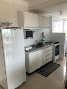 a kitchen with white cabinets and a refrigerator at Residencial Galápagos in Imbituba
