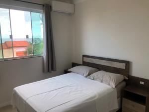 1 cama en un dormitorio con ventana grande en Residencial Galápagos, en Imbituba