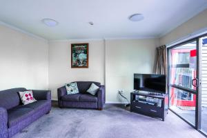 a living room with two purple couches and a tv at Aspen Lodge Backpackers in Queenstown