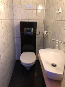 a bathroom with a white toilet and a sink at Tanie Pokoje Blisko Lotniska in Poznań