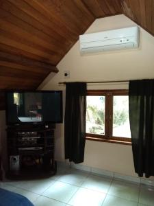 a living room with a flat screen tv and a window at Acomodação Penedo in Penedo