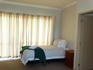 a bedroom with a bed and a large window at Kauri Lodge Karapiro in Karapiro