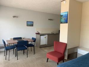 a room with a table and chairs and a kitchen at Ala Moana Motel in Paihia