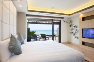 a bedroom with a bed and a television and the ocean at Dusit Thani Guam Resort in Tumon