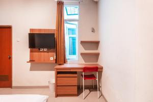 a room with a desk with a tv and a window at The Kartini 8 Residence - Mangga Besar in Jakarta
