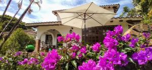 una casa con fiori viola e un ombrello di Linda Casa Condominio Miraflores a Fusagasugá