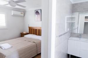 - une chambre blanche avec un lit et un lavabo dans l'établissement Singleton Valley Accommodation, à Singleton