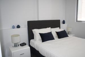 a bedroom with a large white bed with blue pillows at North Sydney Wyndel Apartments-MIL1005 in Sydney
